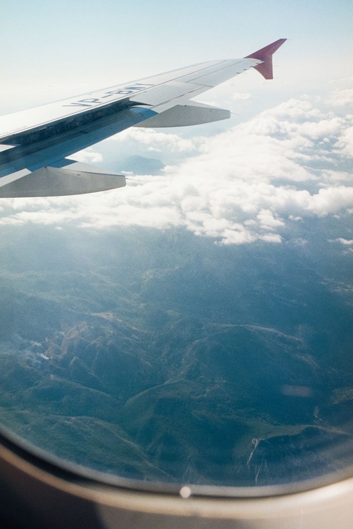 Stunning aerial view from an airplane window showing clouds and mountains below.