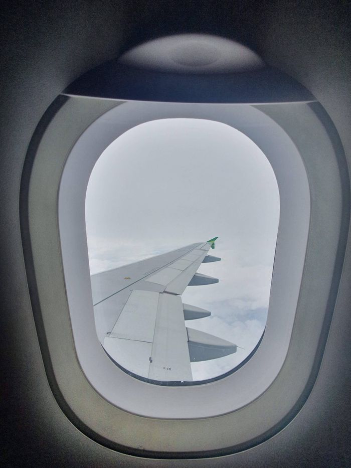 A scenic view of an airplane wing through the window, capturing the essence of air travel at high altitude.