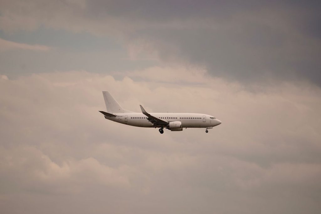 A commercial airplane flying through a cloudy sky during the day, highlighting air travel.