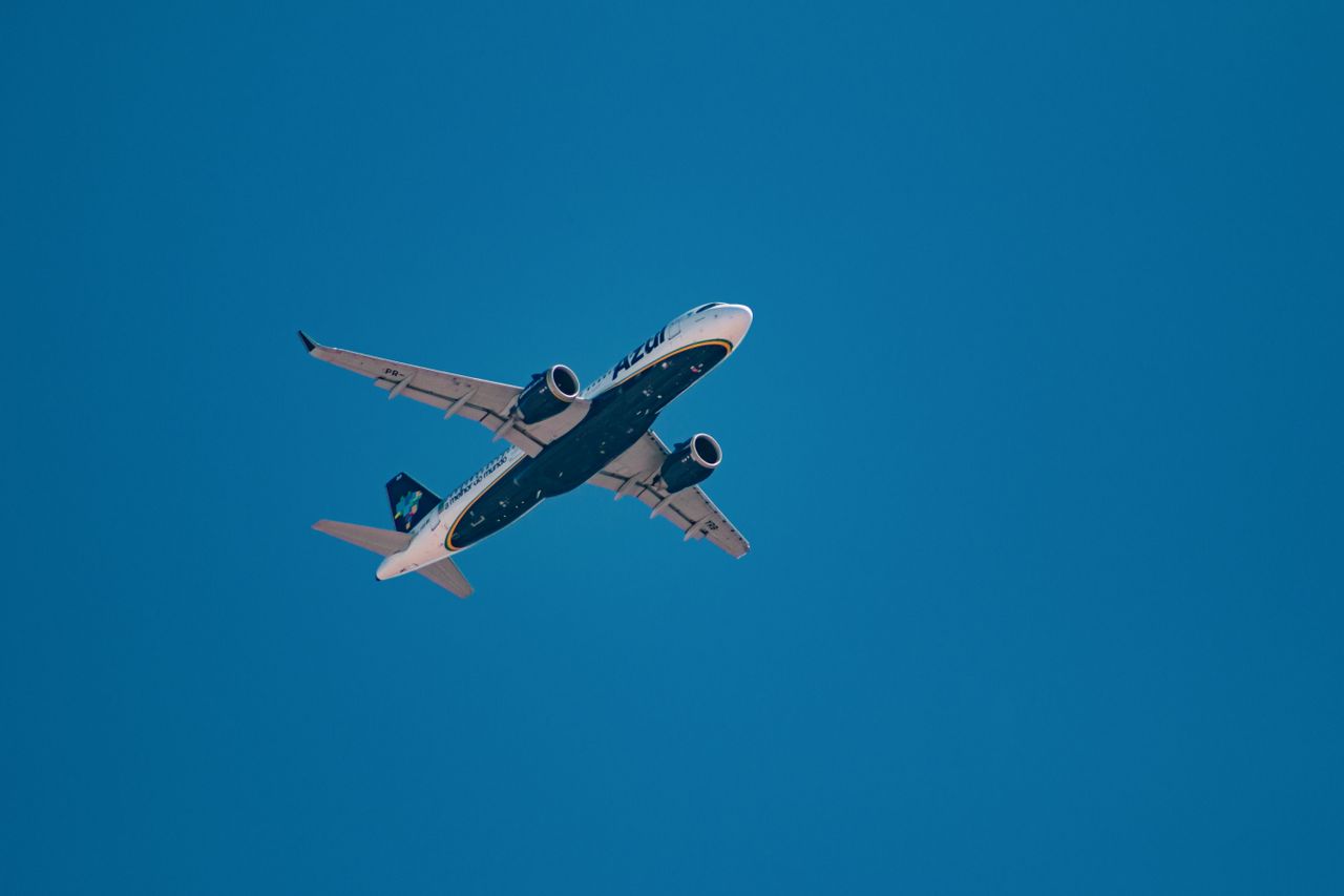 A commercial aircraft flying high against a vibrant blue sky on a sunny day.